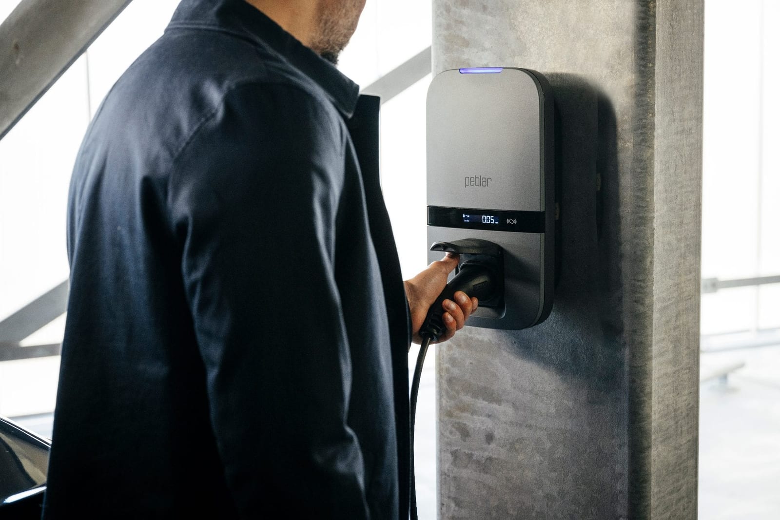 Gebruiker koppelt de laadkabel aan een Peblar Business laadstation