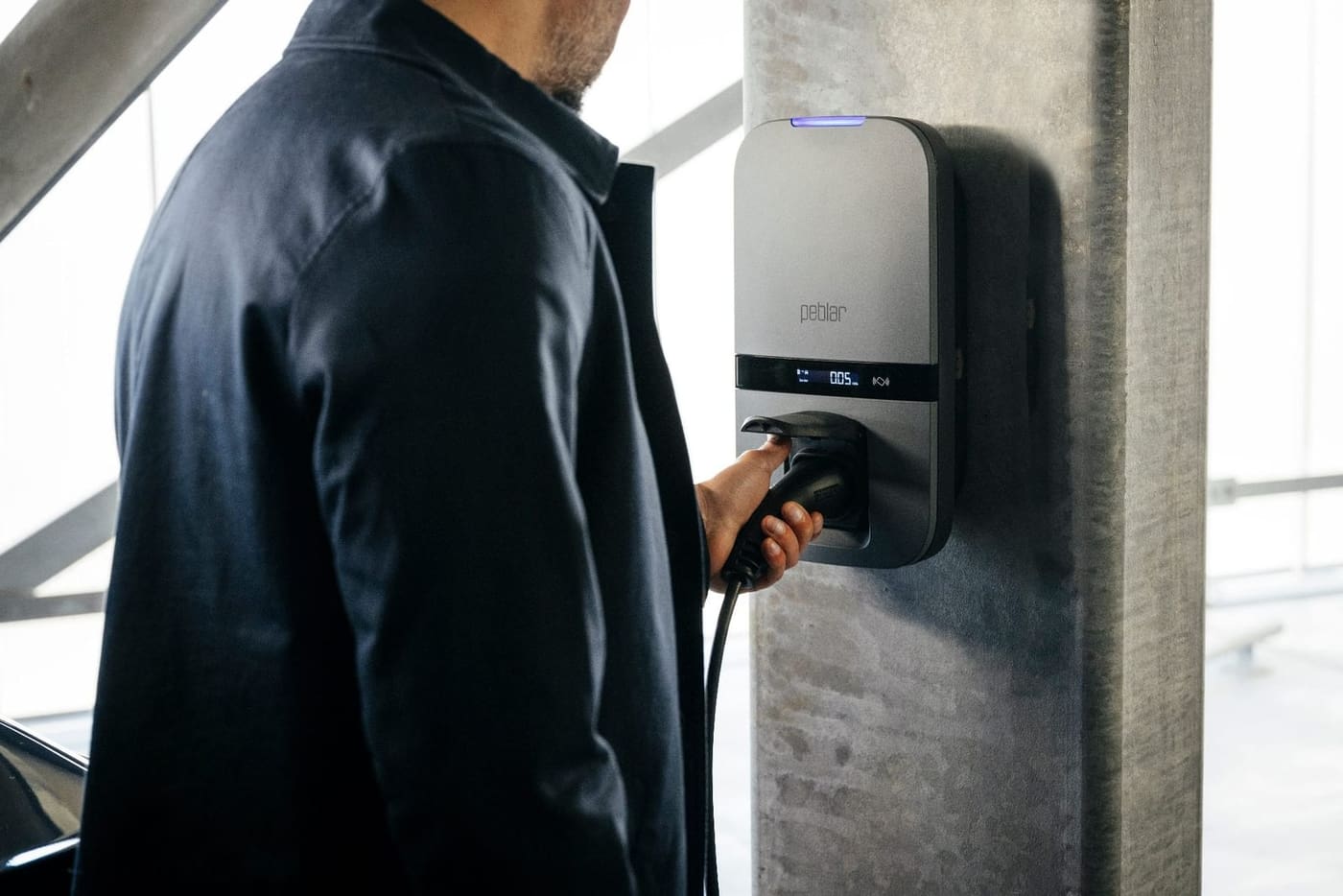 Gebruiker koppelt de laadkabel aan een Peblar Business laadstation