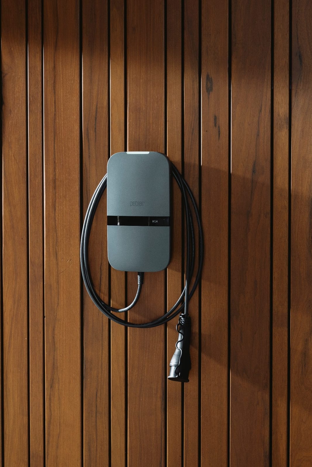 Peblar Home laadstation aan een houten gevel