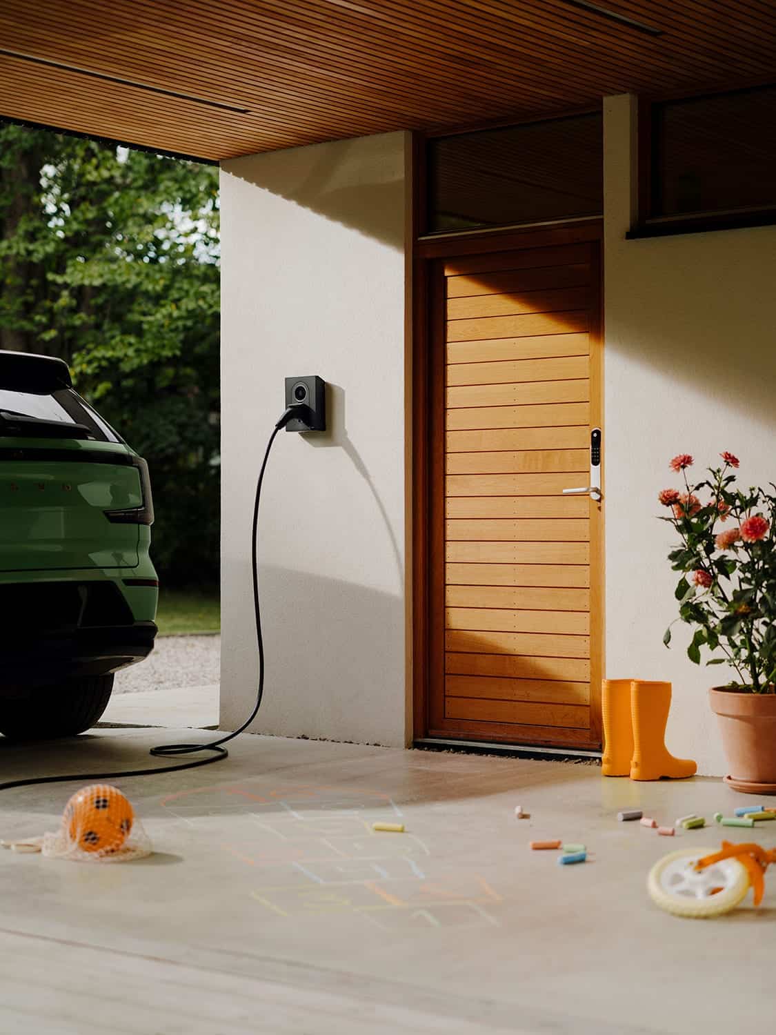 Zaptec Go 2 aan de gevel van een woning, met een wagen die laadt op de oprit