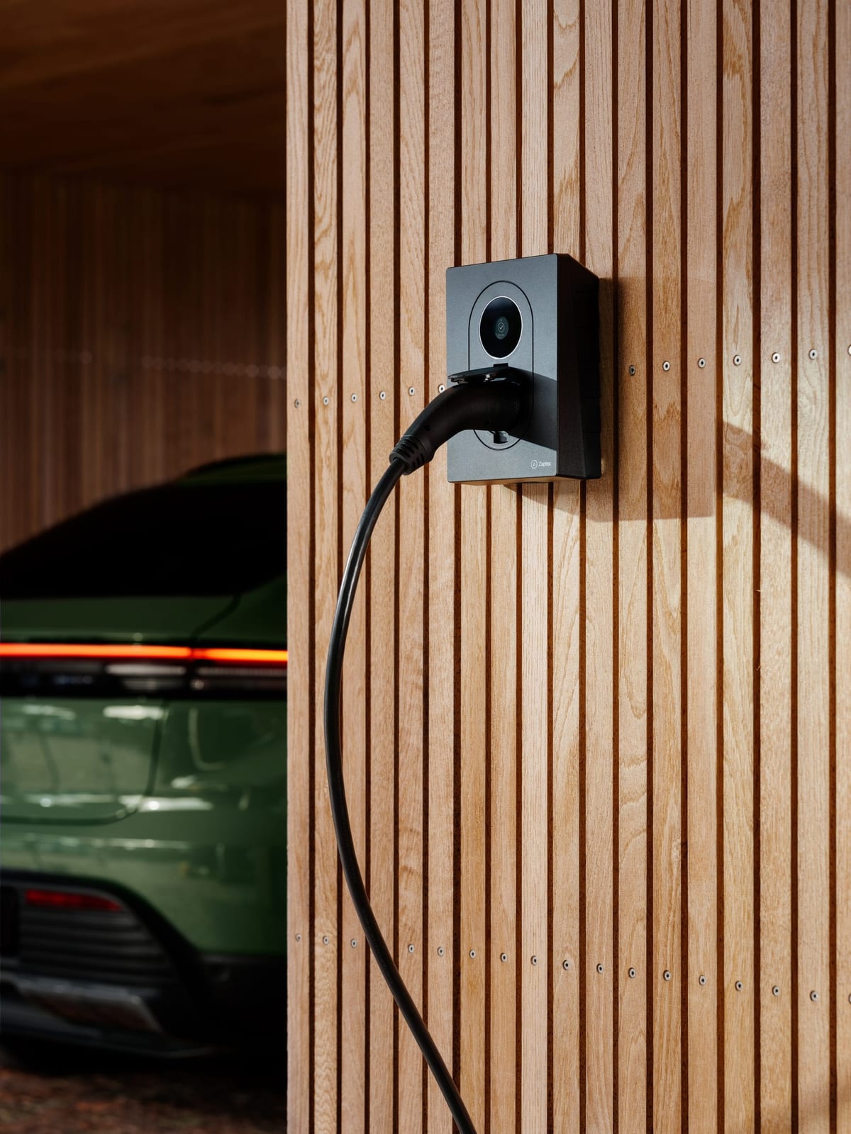 Zaptec laadstation naast een elektrische wagen in een woning